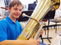 Male Pupil Playing Tuba In High School Orchestra