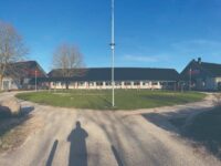 Indgangen til Tjørnegårdskolen hvor besøgende fremover blive mødt af legende børn og en skole med træbeklædte og grønne facader. (Pressefoto)